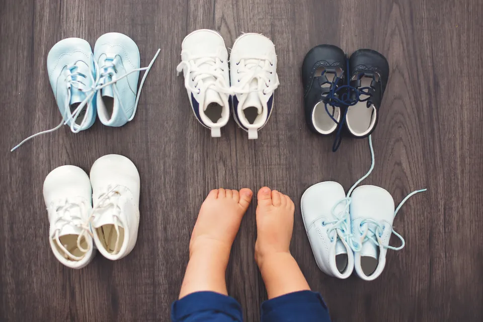 Babyfüße zwischen mehreren Paar ersten Schuhen